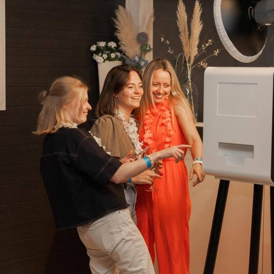 Drie gasten poseren naast de photobooth