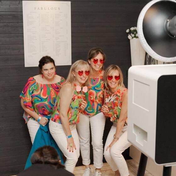 Drie gasten in feestkledij naast de photobooth