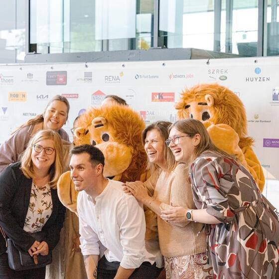 Gasten met de mascottes voor de sponsorwand