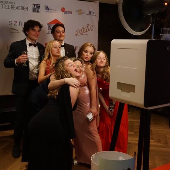 Gasten in avondkledij bij de photobooth